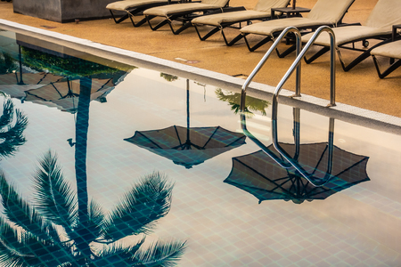 Beautiful luxury outdoor swimming pool with umbrella and chair in hotel and resort for travel and vacationの写真素材