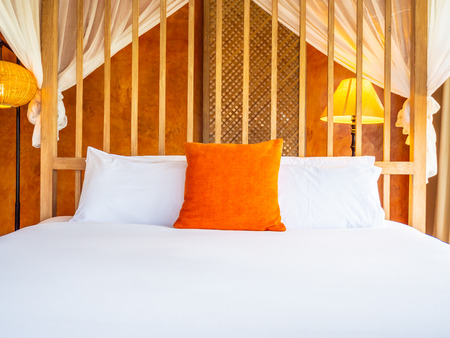 Comfortable pillow on bed with light lamp decoration in hotel bedroomの写真素材