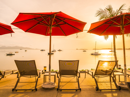 Umbrella and chair around outdoor swimming pool in hotel and resort at sunrise timeの写真素材