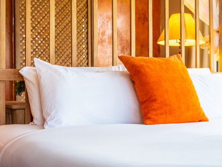 Comfortable pillow on bed with light lamp decoration in hotel bedroomの写真素材