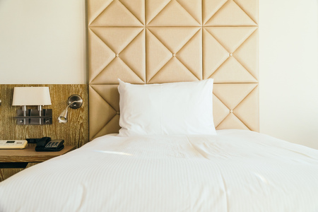 White comfortable pillow on bed decoration with light lamp in hotel bedroom interiorの写真素材