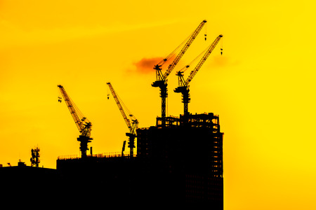 Beautiful Silhouette crane under construction building at sunset time