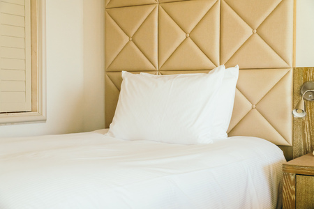 White comfortable pillow on bed decoration with light lamp in hotel bedroom interiorの写真素材