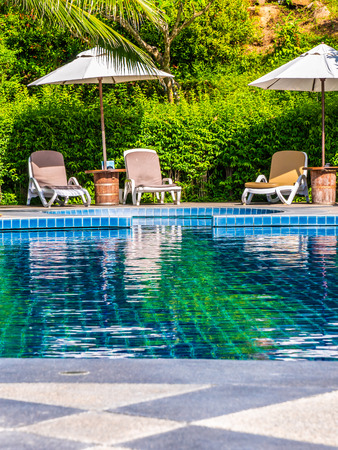 Umbrella and chair around luxury outdoor swimming pool in hotel and resort for vacation and travelの写真素材