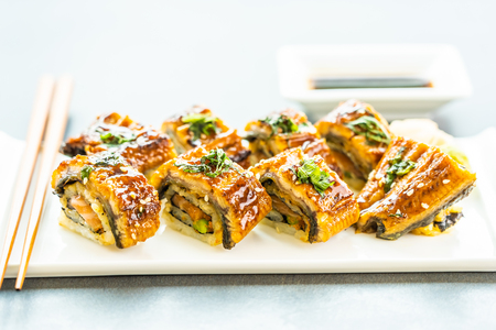 Grilled eel or unagi fish with salmon and vegetable inside sushi maki roll and sweet sauce on white plate - Japanese food styleの写真素材