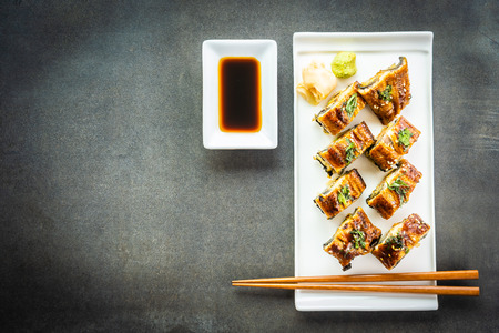 Grilled eel or unagi fish with salmon and vegetable inside sushi maki roll and sweet sauce on white plate - Japanese food styleの写真素材