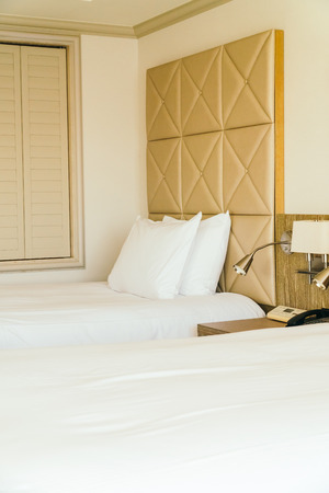 White comfortable pillow on bed decoration with light lamp in hotel bedroom interiorの写真素材