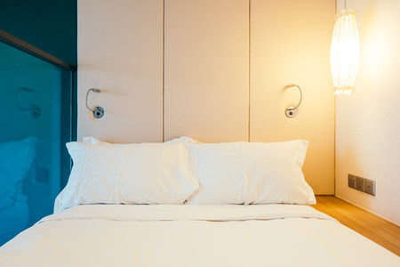 White comfortable pillow on bed decoration in hotel bed room interiorの写真素材