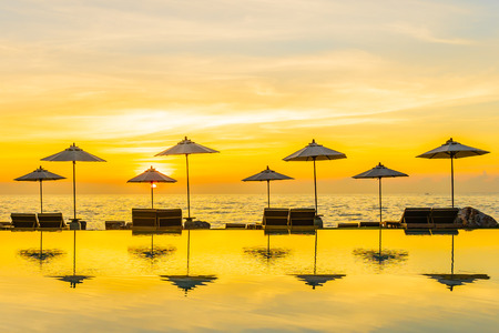 Umbrella and chair around swimming pool in resort hotel for leisure travel and vacation neary sea ocean beach at sunset or sunrise timeの写真素材