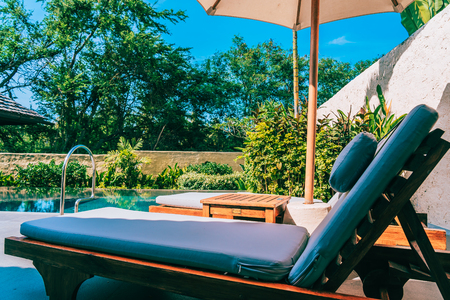 Umbrella and chair around swimming pool neary beautiful landscape of sea ocean beach with blue sky and white cloud for leisure travel and vacationのeditorial素材