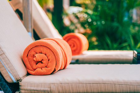 Orange pool towel on deck chair around swimming pool in hotel resort for vacation travel and leisureの写真素材