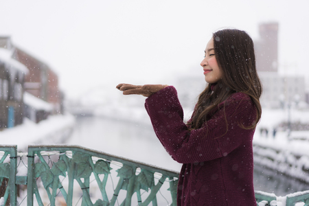 Beautiful young asian woman smile and happy with travel trip at Otaru canal Hokkaido Japan in Snow and Winter Seasonの写真素材