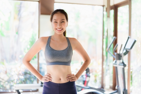 Portrait beautiful young asian woman exercise with fitness equipment in gym interior for good healthyの写真素材