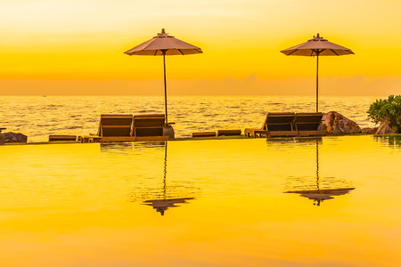 Umbrella and chair around swimming pool for leisure travel and vacation nearby sea ocean beach at sunset or sunrise timeの写真素材