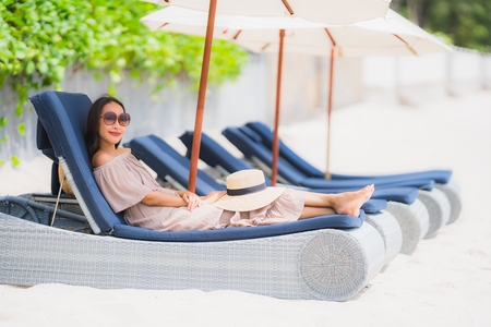 Portrait beautiful young asian woman on the deck chair with umbrella around beach sea ocean for leisure travel and vacation conceptの写真素材