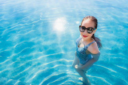 Portrait beautiful young asian woman smile happy relax around swimming pool in hotel resort for leisure travel and vacation conceptの写真素材