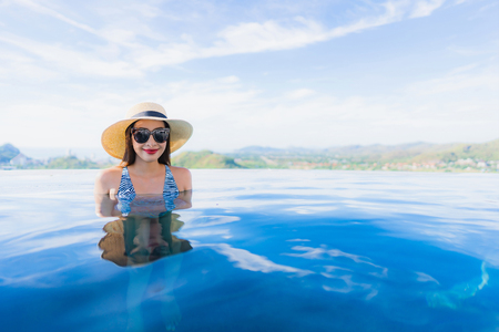 Portrait beautiful young asian woman smile happy relax around swimming pool in hotel resort for leisure travel and vacation conceptの写真素材