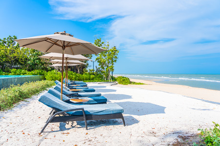 Umbrella and chair on the beach sea ocean with blue sky and white cloud for leisure travel and vacationの写真素材