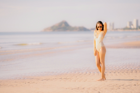 Portrait young beautiful asian woman walk smile happy on the beach sea ocean with sunglasses for leisure travel in holiday vacationの写真素材