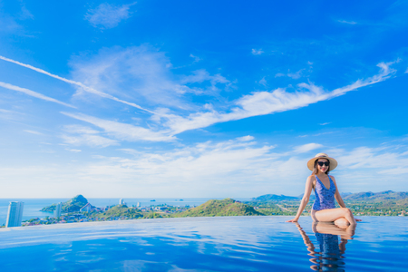 Portrait beautiful young asian woman smile happy relax around swimming pool in hotel resort with sea and ocean view for leisure travel in holiday vacationの写真素材