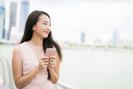 Beautiful asian woman using smartphone or mobile phone for talking or textの写真素材