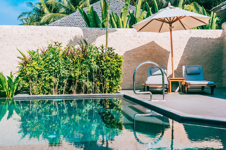 Umbrella and chair around swimming pool neary beautiful landscape of sea ocean beach with blue sky and white cloud for leisure travel and vacationのeditorial素材