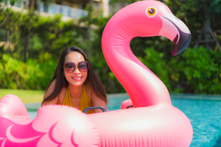 Portrait beautiful young asian woman on the flamingo inflatable float in swimming pool at hotel resort for leisure holiday vacation conceptの写真素材