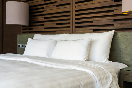 Beautiful luxury comfortable pillow on bed with light lamp decoration in bedroom interiorの写真素材