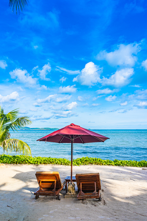 Beautiful landscape of beach sea ocean with empty chair deck and umbrella nearly coconut palm tree with white cloud and blue sky for leisure travel in holiday vacationの写真素材