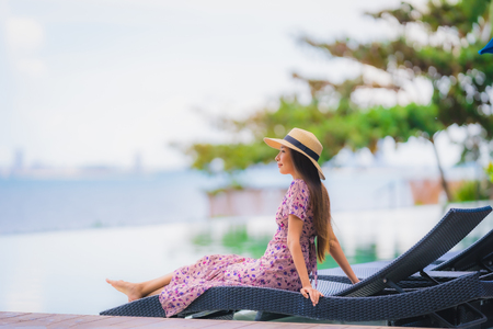 Portrait beautiful young asian woman happy smile relax in swimming pool at hotel resort neary sea ocean beach on blue sky for leisure travel in vacationの写真素材