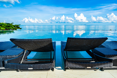 Umbrella and chair around swimming pool in hotel resort neary sea ocean beach for leisure relax in holiday vacationの写真素材