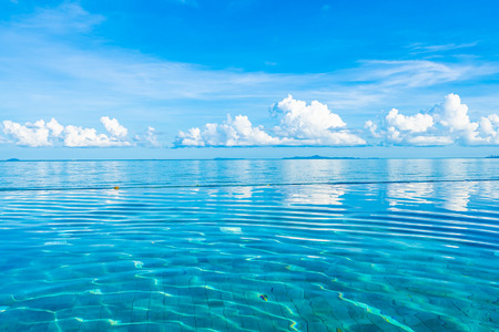 Beautiful outdoor swimming pool in hotel resort nearly sea ocean beach on white cloud blue sky for...