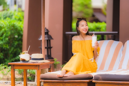 Portrait beautiful young asian woman leisure relax smile and happy with coconut juice around swimming pool in hotel resort for holiday vacation conceptの写真素材
