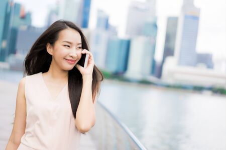 Beautiful asian woman using smartphone or mobile phone for talking or textの写真素材