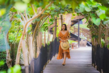 Portrait beautiful young asian woman walk on path walk in the garden with happy smile relaxの写真素材