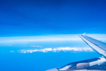 Aerial view of airplane wing with blue sky and white cloudの写真素材