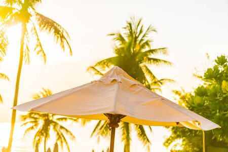 Beautiful outdoor tropical nature landscape of swimming pool in hotel resort with coconut palm tree umbrella and chair nearly sea ocean beach at sunrise timeの写真素材