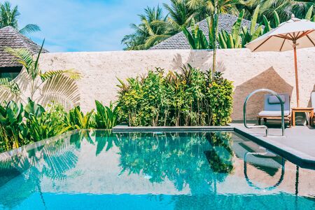 Umbrella and chair around swimming pool neary beautiful landscape of sea ocean beach with blue sky and white cloud for leisure travel and vacationの写真素材
