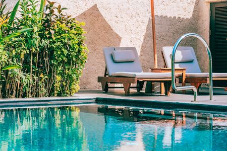 Umbrella and chair around swimming pool neary beautiful landscape of sea ocean beach with blue sky and white cloud for leisure travel and vacationの写真素材