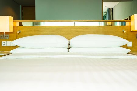 Beautiful luxury comfortable white pillow on bed with light lamp decoration in bedroom interiorの写真素材