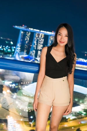 Beautiful Asian women smile and happy with singapore city view at nightのeditorial素材