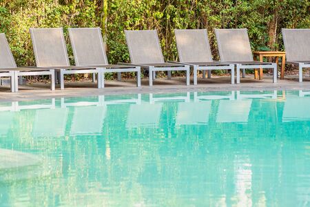Empty chair around swimming pool in hotel resort for travel leisure and vacation conceptの写真素材