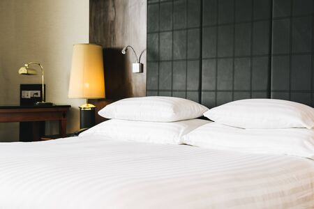 Beautiful luxury comfortable white pillow and blanket on bed with light lamp furniture decoration in hotel bedroom interiorの写真素材