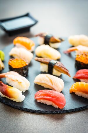 Nigiri sushi set with salmon tuna fish shrimp prawn eel shell and other sashimi on black slate - Japansese food styleの写真素材