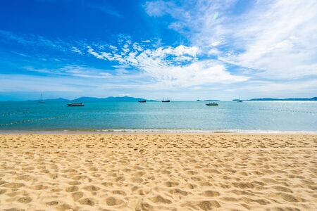 Beautiful tropical beach sea and ocean with coconut palm tree  and umbrella and chair on blue sky and white cloud for holiday vacation travelの写真素材
