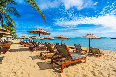 Beautiful tropical beach sea and ocean with coconut palm tree  and umbrella and chair on blue sky and white cloud for holiday vacation travelの写真素材
