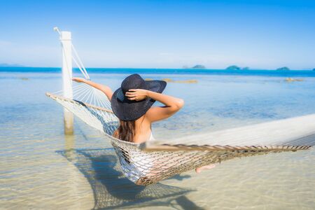 Portrait beautiful young asian woman sitting on hammock around sea beach ocean for relax in holiday vacation travel conceptの写真素材