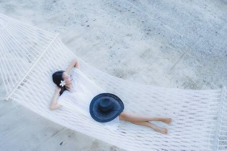 Portrait beautiful young asian woman sitting on hammock around sea beach ocean for relax in holiday vacation travel conceptの写真素材