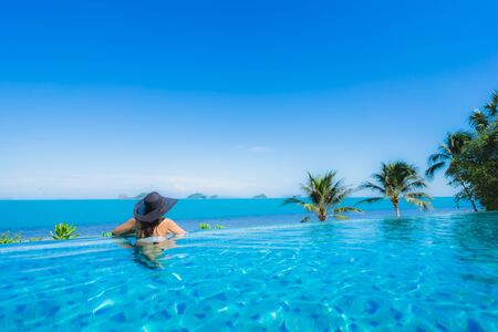 Portrait beautiful young asian woman relax in luxury outdoor swimming pool in hotel resort nearly beach sea ocean for holiday vacation conceptの写真素材