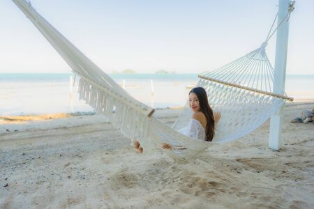 Portrait beautiful young asian woman sitting on hammock around sea beach ocean for relax in holiday...